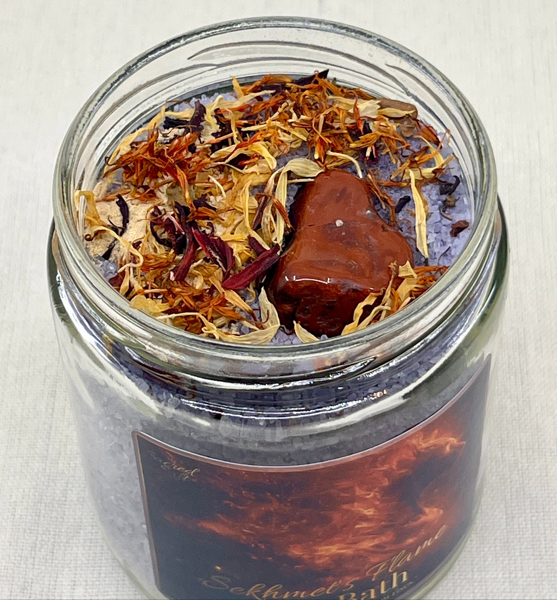 Glass jar with dried herbs and a label on a light background