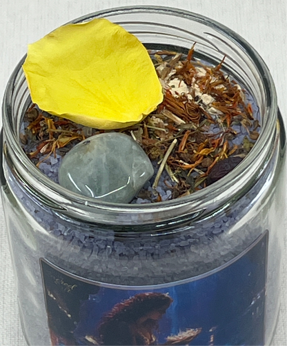 Jar with a yellow petal, crystal, and dried herbs on a white background